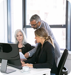 Team collaborating at a desk while customizing a view on their computer.